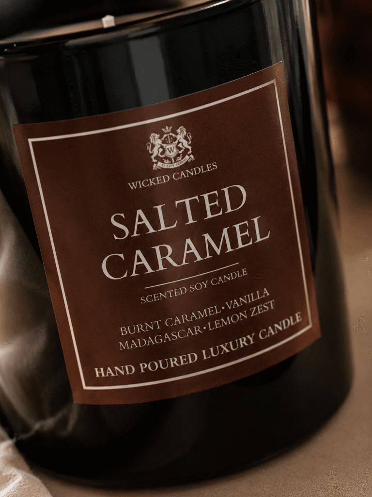 Luxury Salted Caramel αρωματικό κερί σόγιας Wicked Candles με νότες burnt caramel, vanilla, Madagascar και lemon zest σε glossy μαύρο γυάλινο βάζο με minimal beige aesthetic decor.